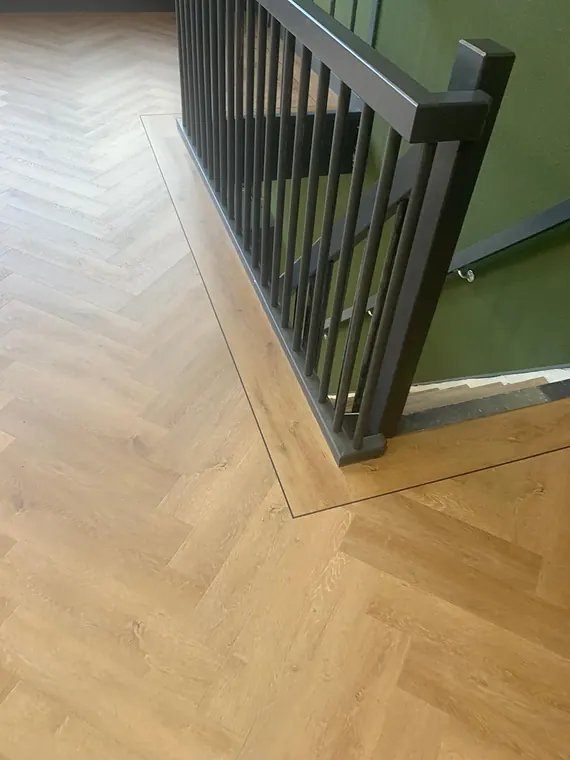 Warme eiken visgraatvloer met glazen balustrade bij de trapopgang